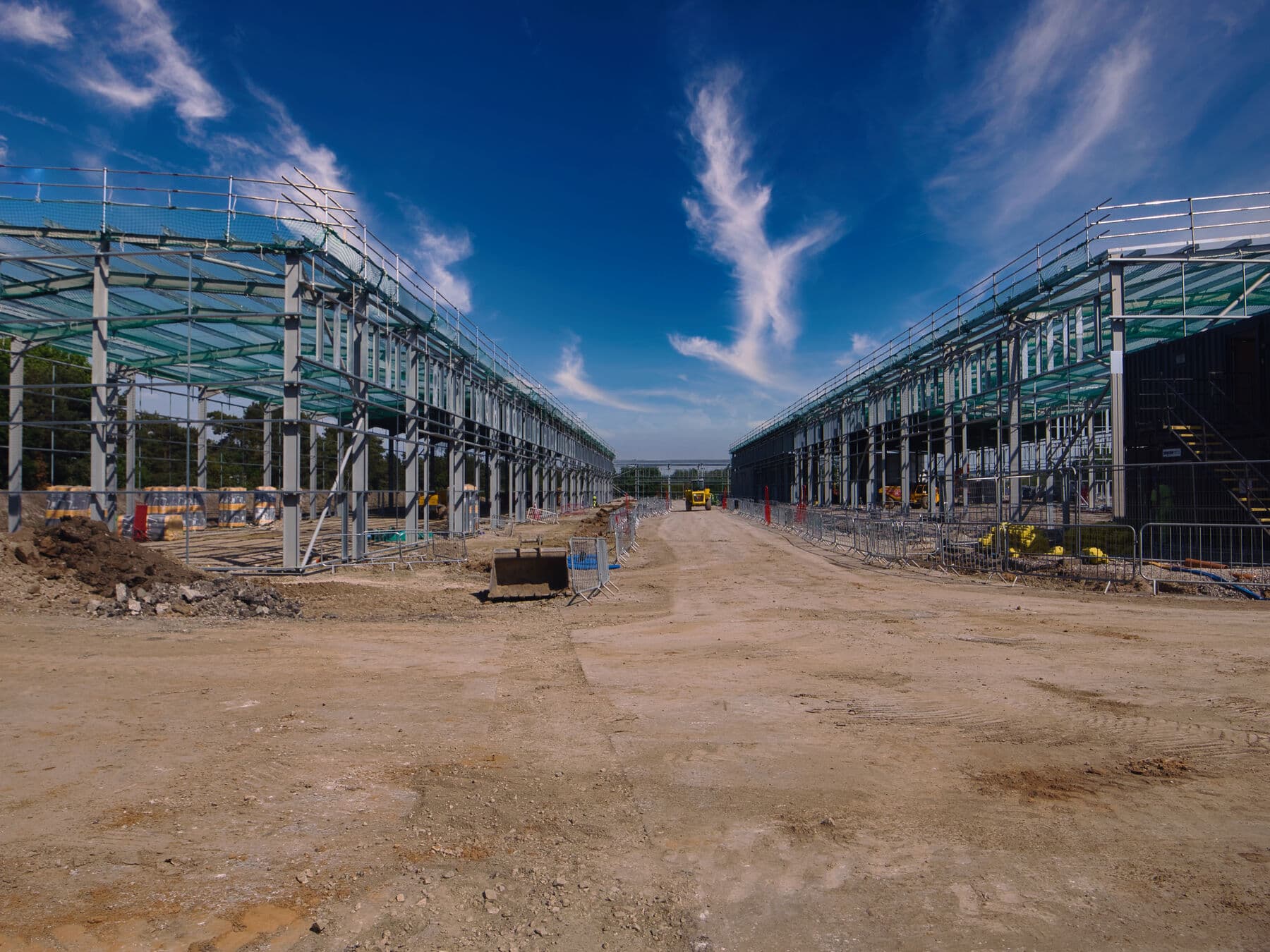 Ground-level view down the length of the site with the steel frames either side